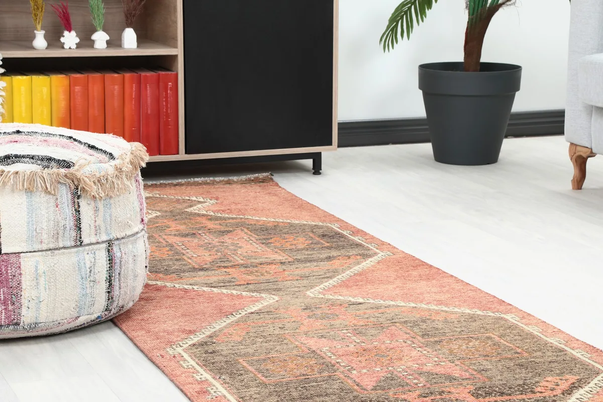 Close-up view of the runner rug in a room setting, showing its texture next to a decorative pouf.