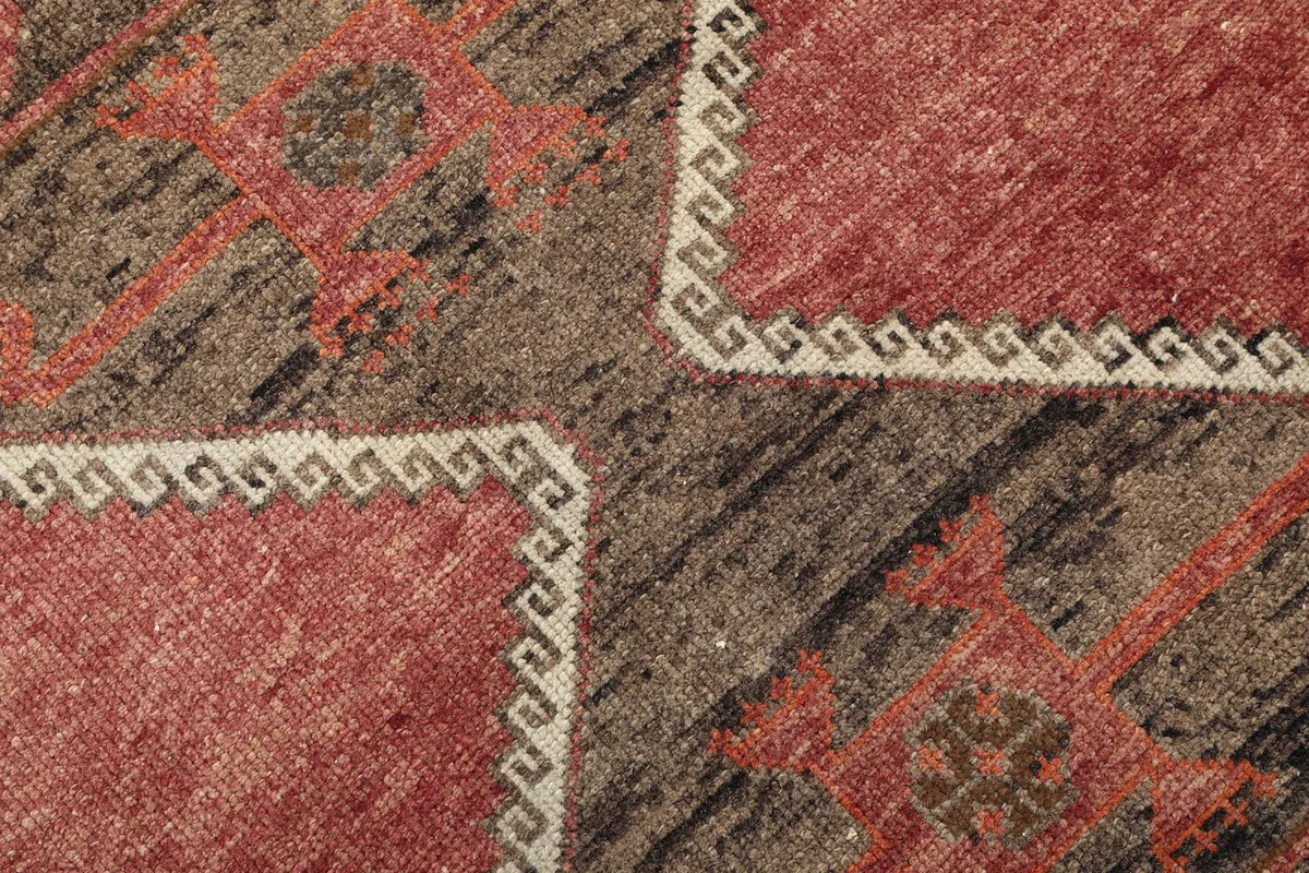 Extreme close-up of the intricate geometric motifs and beige border details on the rug.