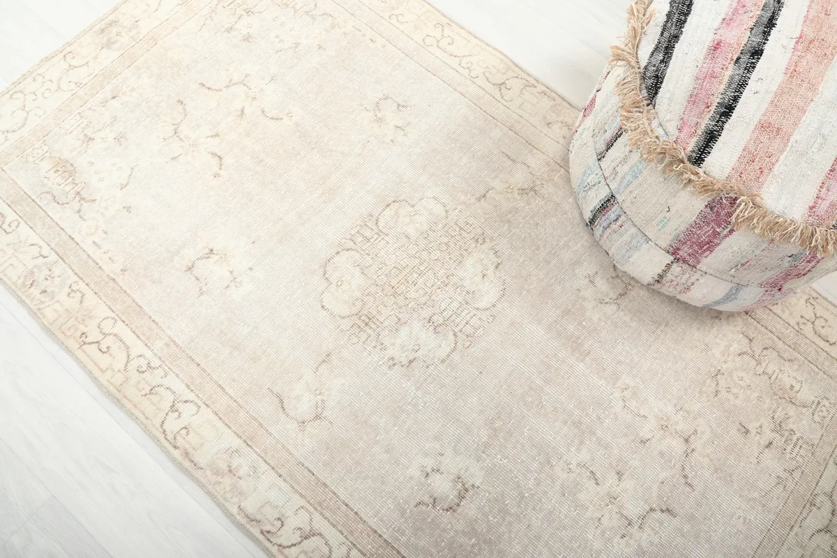Diagonal view across the beige rug, emphasizing the central medallion and border designs.