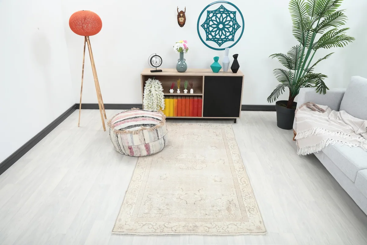 Vintage beige Anatolian rug shown in a living room setting with a sofa and decor.