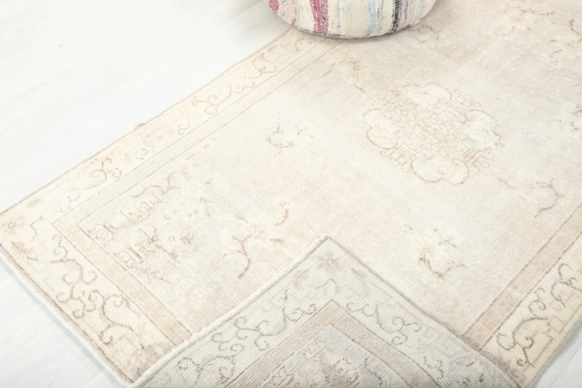 View of the beige rug folded to show its flexibility and the consistency of the pattern.