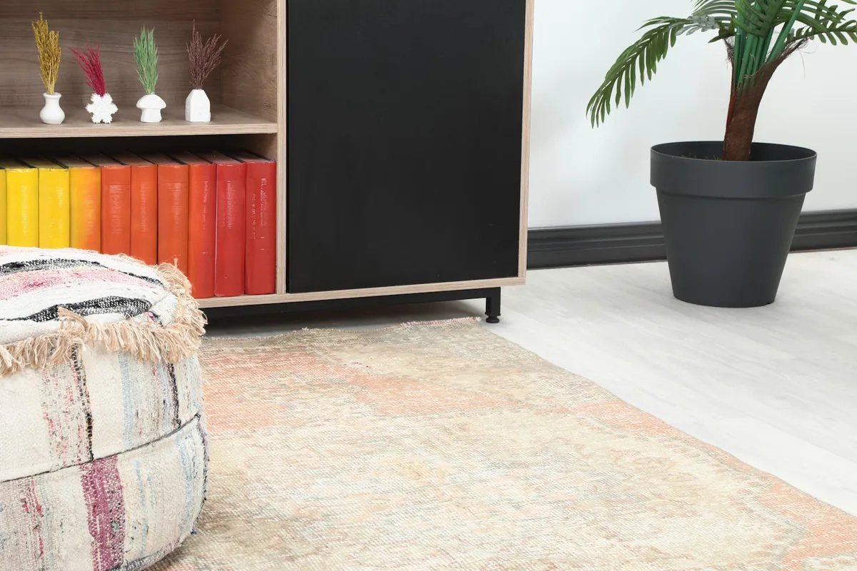 Close-up of the rug's surface next to a pouf, highlighting the colors and subtle wear
