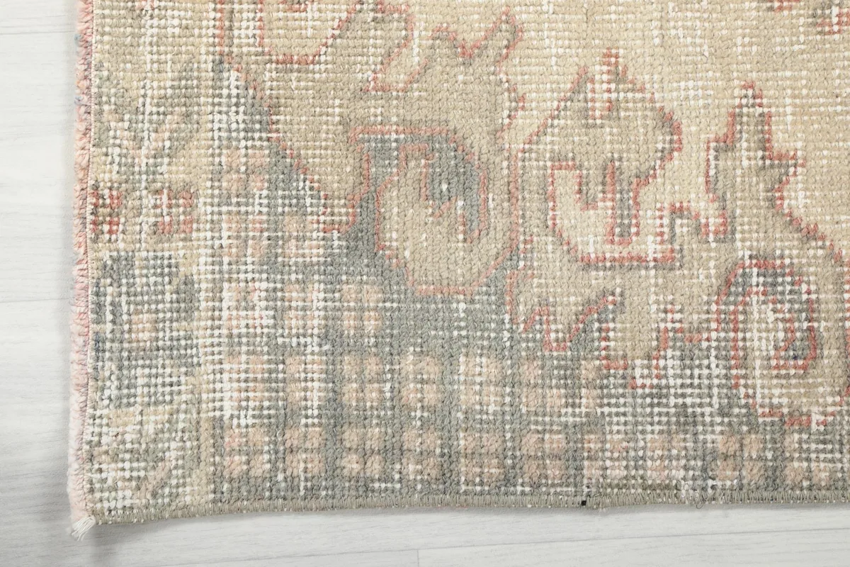 Edge detail of the vintage rug, showing the worn pile and subtle color shifts at the border
