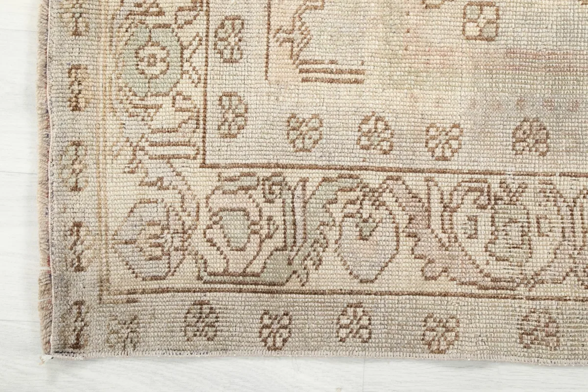 Corner detail of the rug, showing the outer border with its repeating floral and geometric elements.