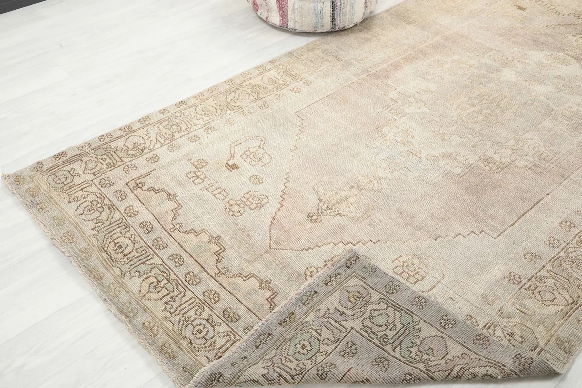 Corner of the rug folded back slightly to reveal the cotton foundation and the reverse side of the knotting.