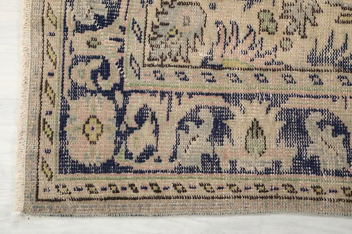 Corner detail of the rug, highlighting the navy border with floral motifs and beige accents