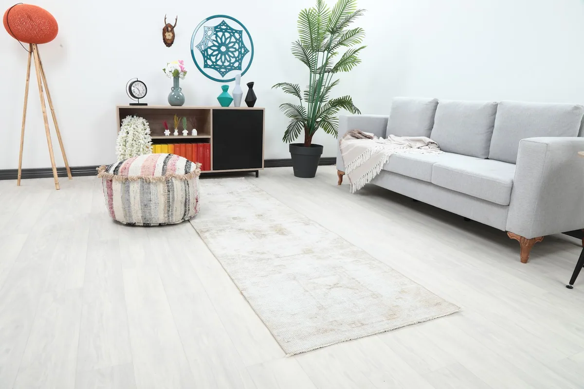 Angled view of the cream runner rug in a contemporary room, showing its length next to a sofa.