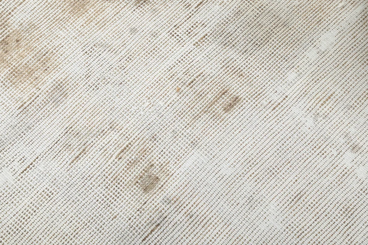 Close-up of the low wool pile and visible cotton foundation through the distressed areas of the rug.