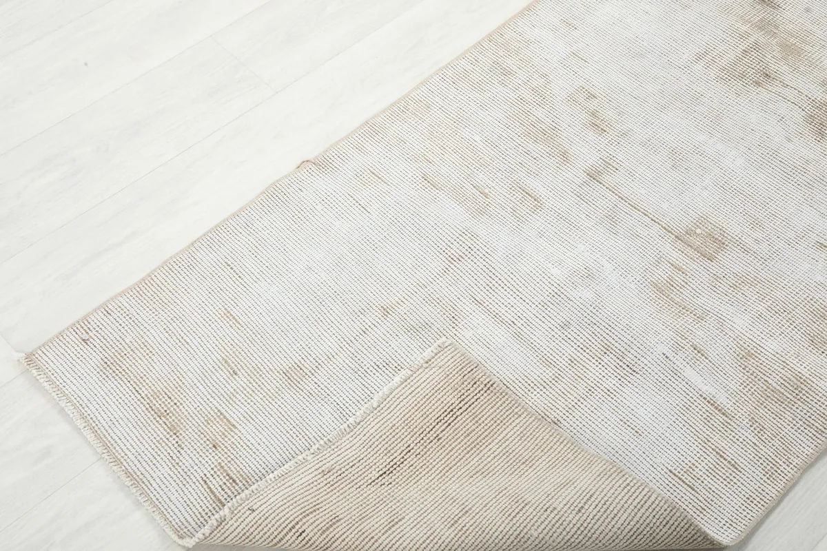 Corner of the runner rug folded to show both the low pile and the tightly woven cotton foundation.