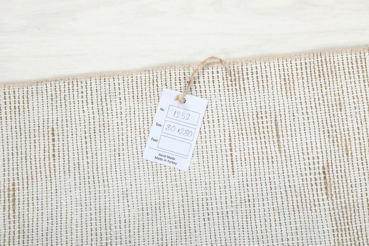 Close-up of the RugsKilim tag attached to the back of the hand-knotted vintage runner rug.