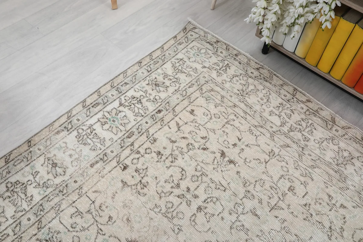 Corner view of the cream and gray rug, emphasizing the detailed border and the soft, muted color palette.