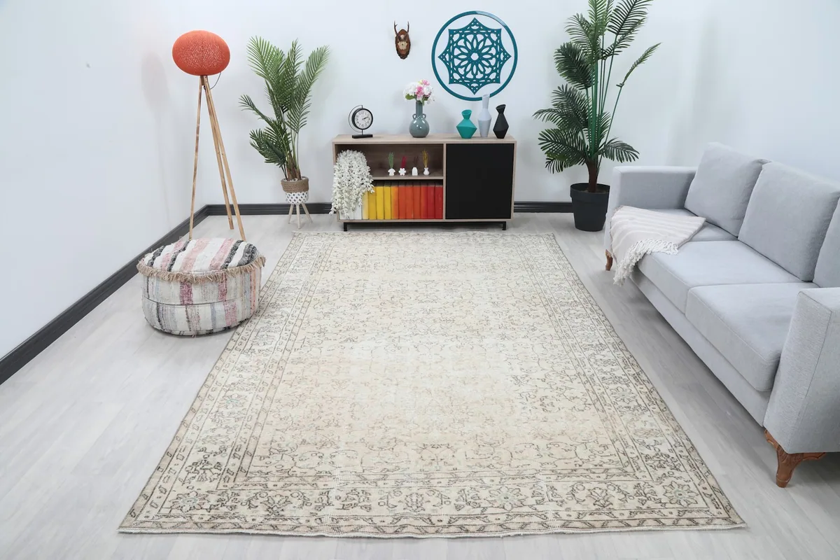 Vintage cream and gray rug displayed in a bright living room setup with a gray sofa and wooden furniture.