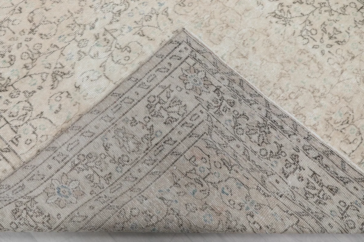 Corner of the rug folded to reveal the backside, showing the tight hand-knotted cotton foundation and wool pile.