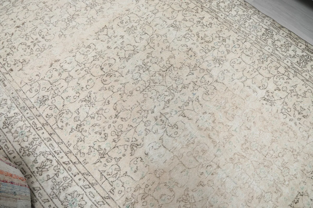 Overhead view showing the subtle color variations and distressed look of the cream and gray vintage rug.