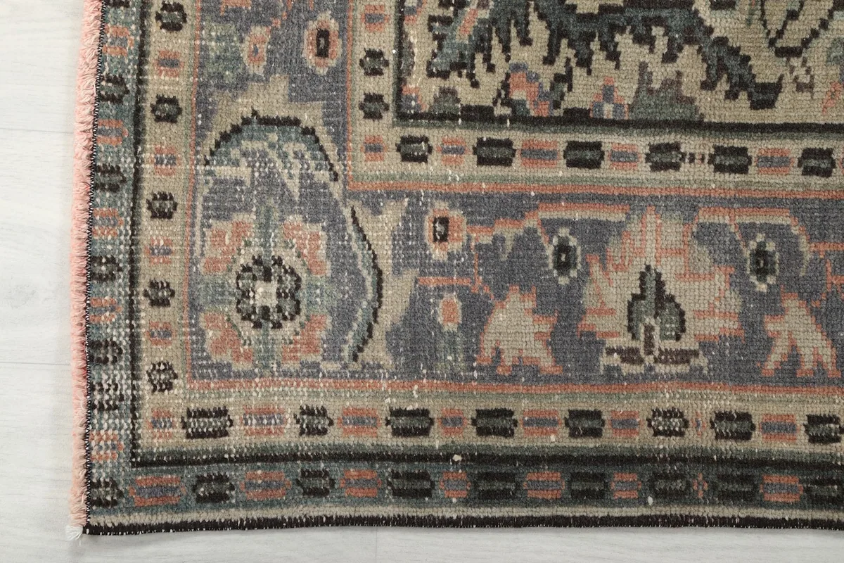 Corner detail of the rug's multi-layered border with geometric and floral elements