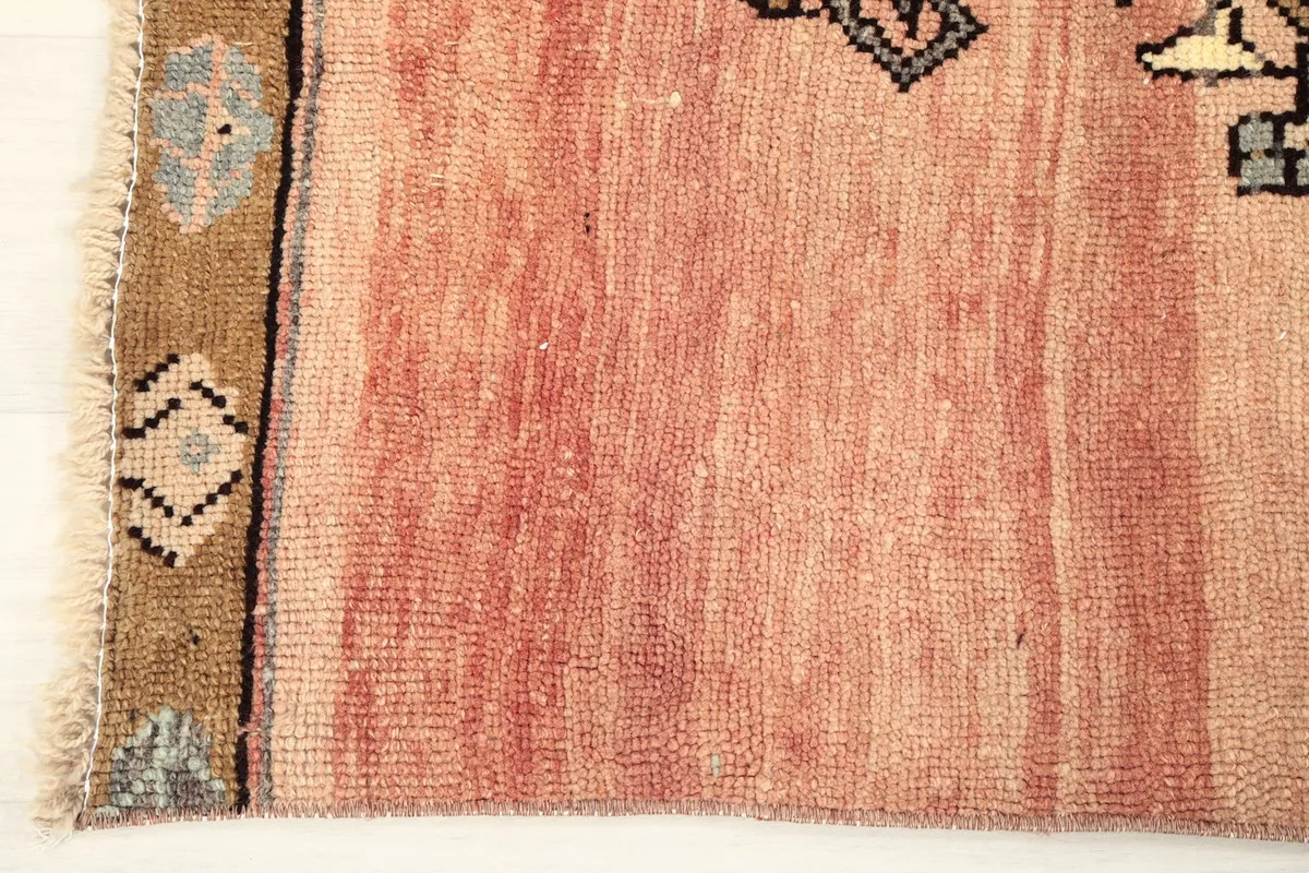 Close-up of the rug's low wool pile and the subtle color striations on the rust field.