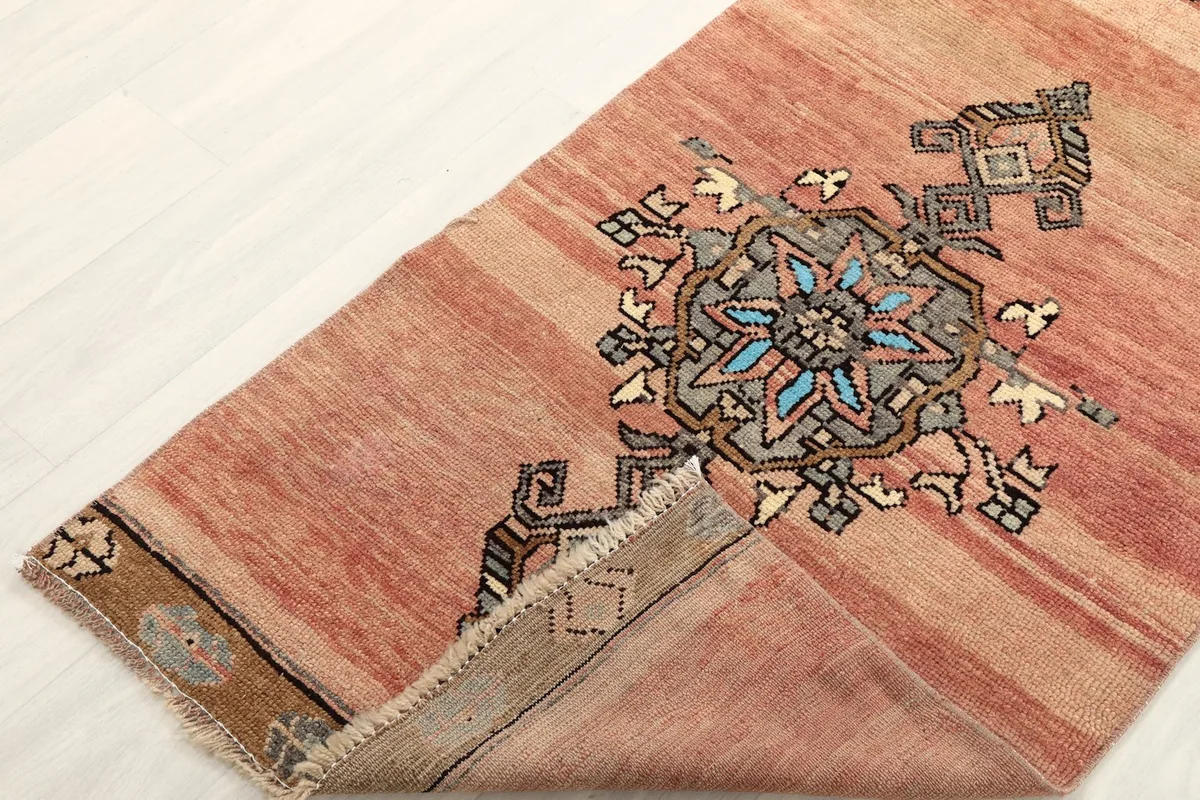 Corner of the rug folded back to show the cotton foundation and the reverse side of the knotting.