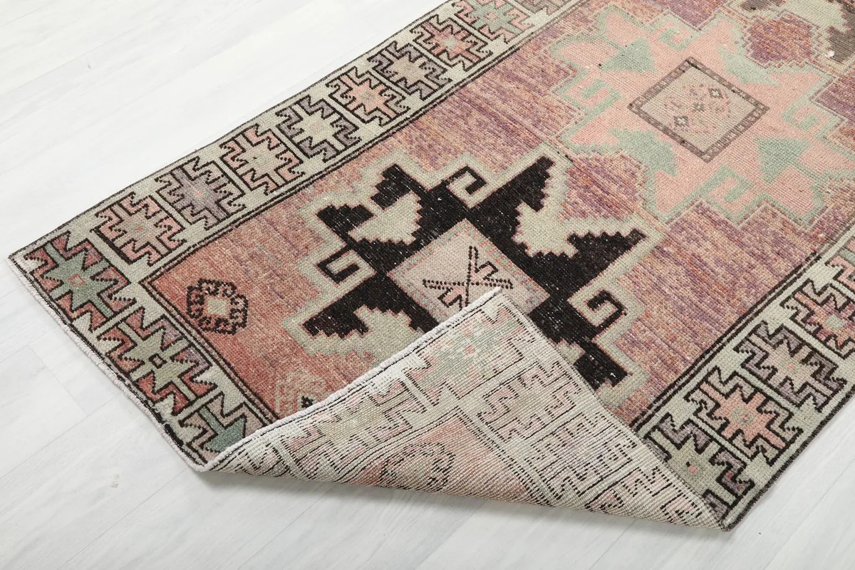 Corner of the rust geometric runner rug folded back to show the reverse side of the hand-knotted construction.