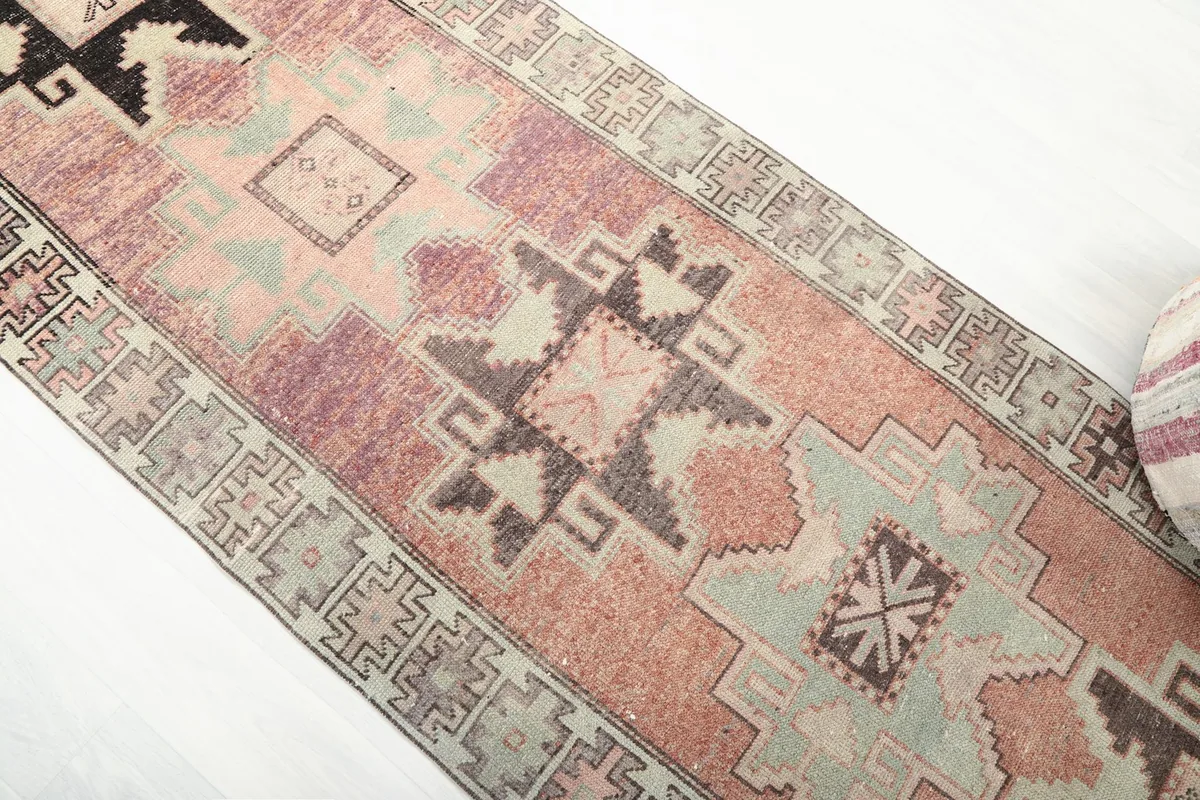 Overhead view of the central and upper sections of the rust and beige vintage runner, highlighting geometric motifs.