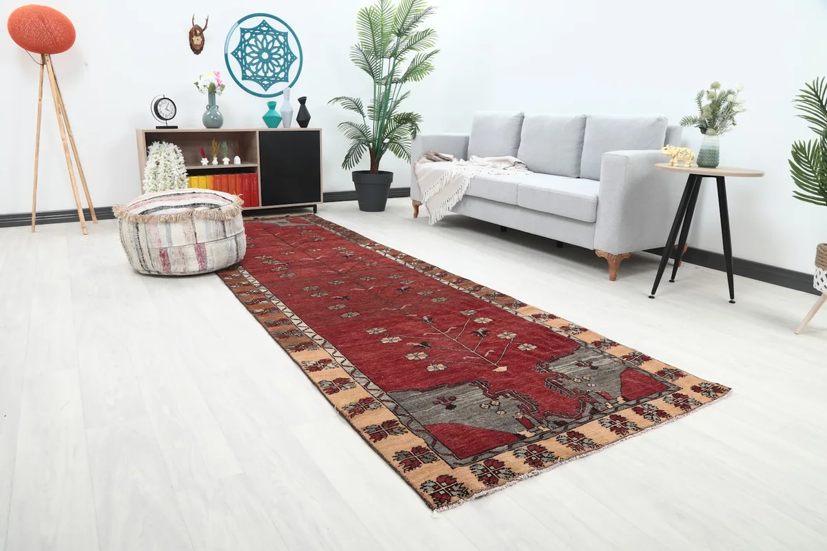 Angled view of the red Anatolian runner in a room, highlighting its placement next to furniture.