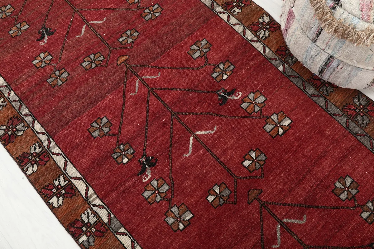 Detailed view of the red field with stylized floral and tree of life motifs.