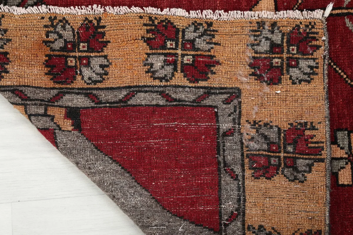 Close-up of the back of the rug where a corner is folded, showing the cotton foundation and hand-knotting.