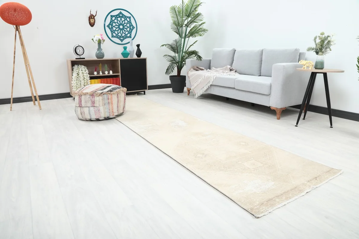 Angled view of the beige runner rug in a living space, highlighting its length and subtle patterns.