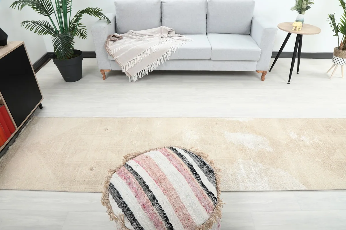 Overhead view of the beige runner rug in a room, showing its placement relative to a sofa and ottoman.