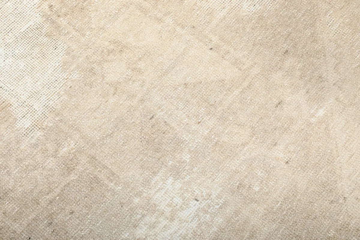 Close-up detail of the hand-knotted wool pile and subtle geometric motifs of the vintage beige runner.