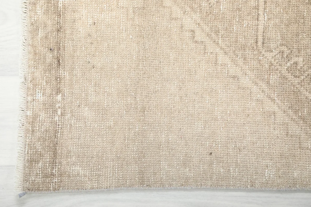 Detail showing the edge and fringe of the beige vintage runner, highlighting the wool and cotton foundation.