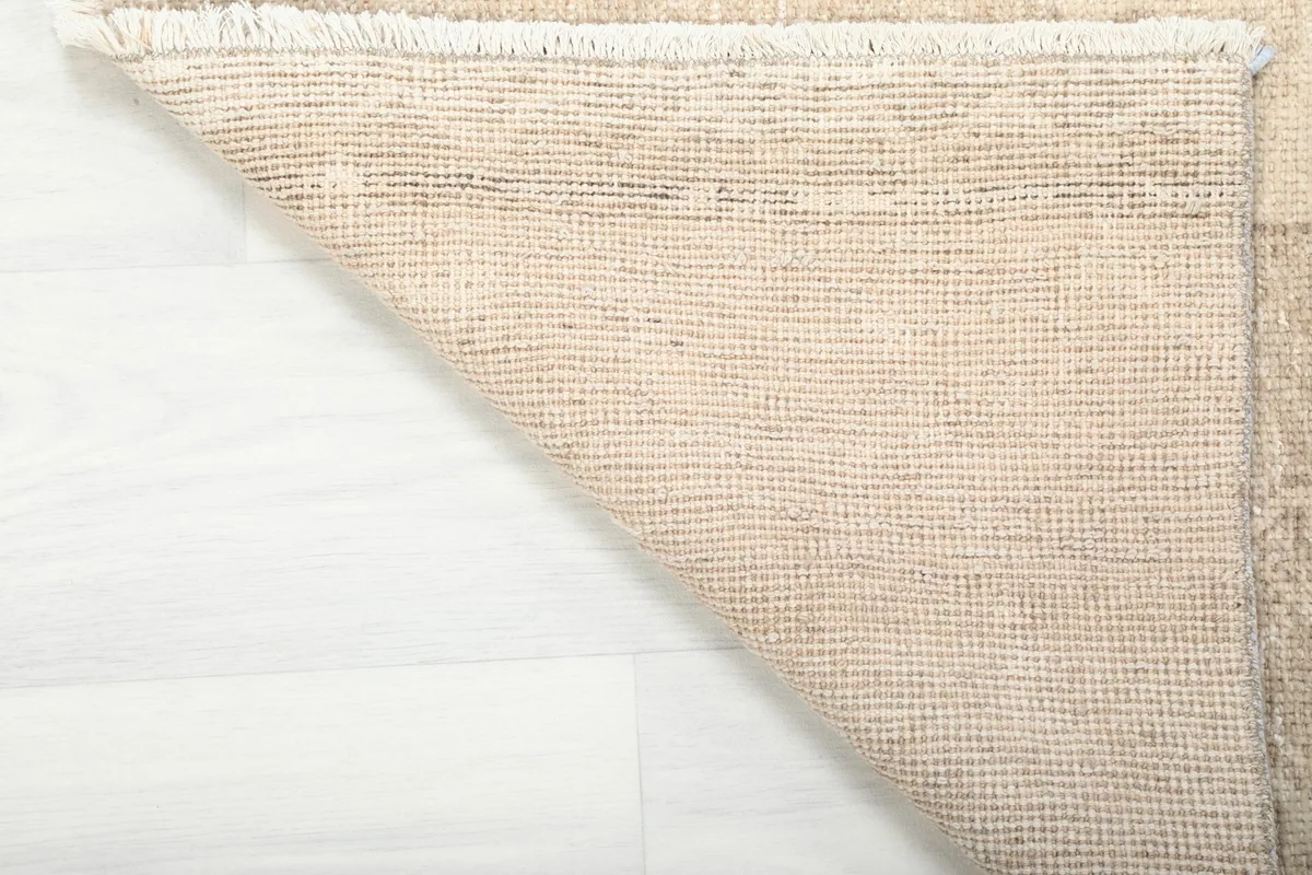 Underside view of the beige runner rug, showing the cotton foundation and knotting structure.