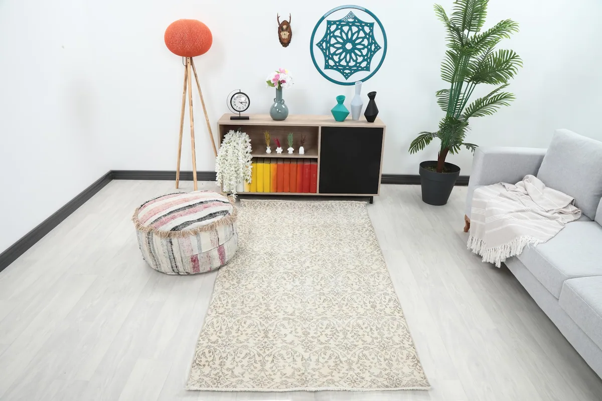 The ivory and gray floral rug displayed in a bright living room setup with a light gray sofa and modern decor.