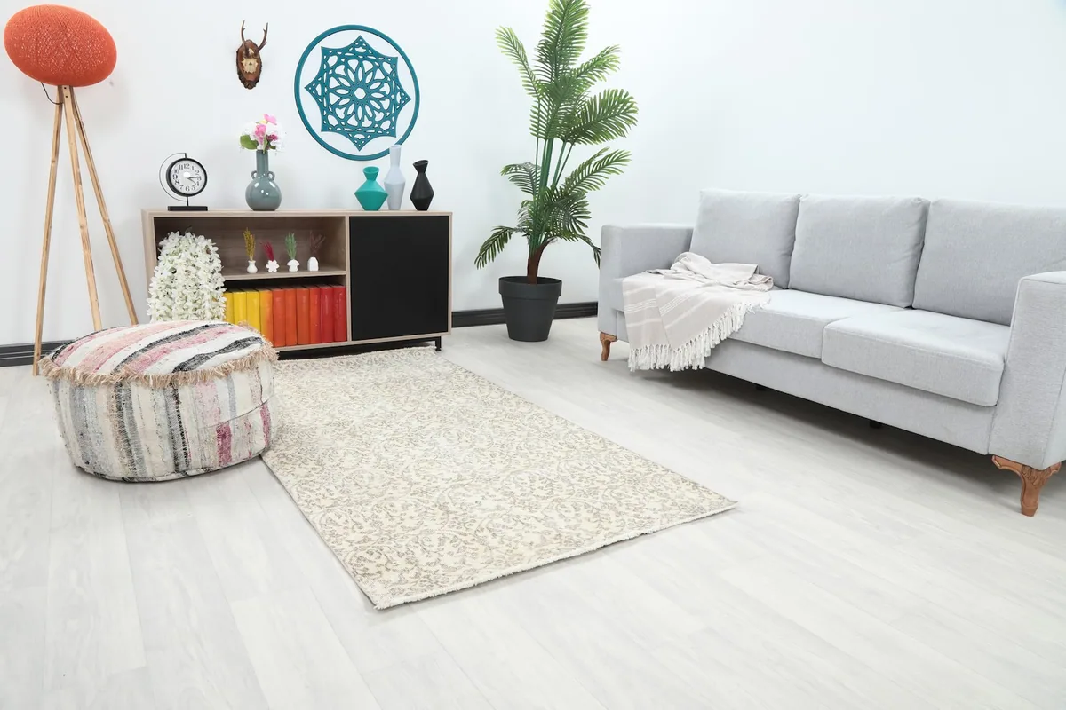 Angle view of the rug in a living room, showing its placement in front of a sofa and a decorative pouf.