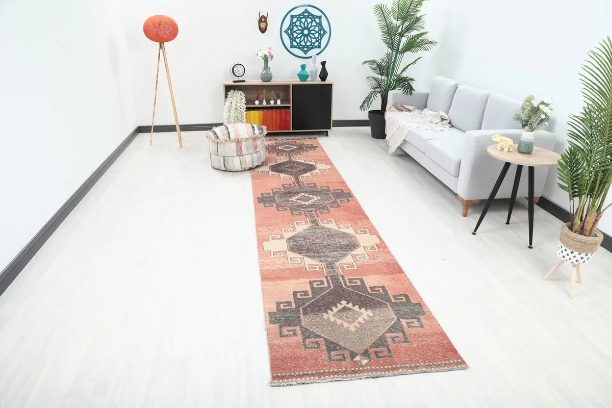 Vintage rust runner rug displayed in a bright hallway setting next to a sofa and decor