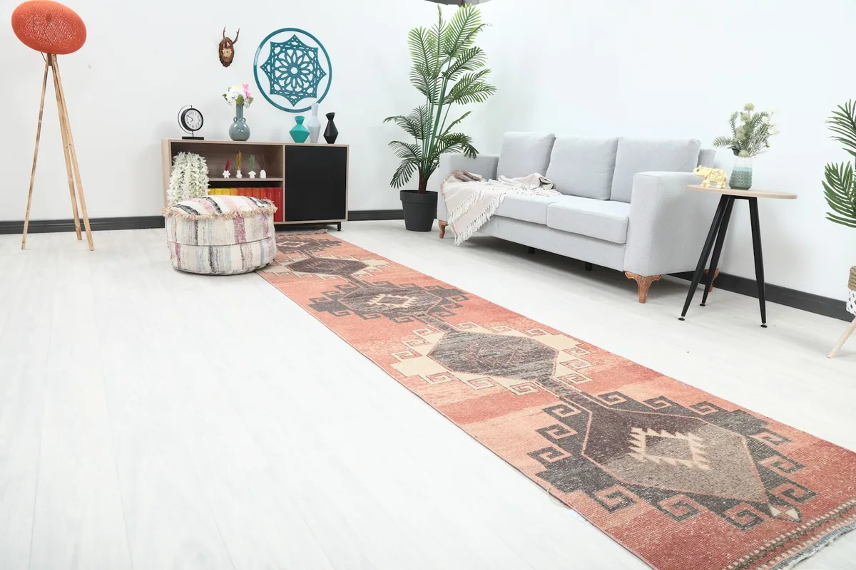 Long view of the rust runner rug extending through a modern living area with a gray couch