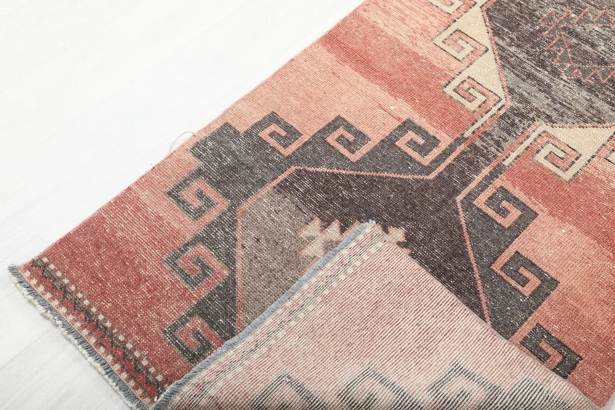 Corner of the runner rug folded back to reveal the cotton foundation and the reverse side of the knotting