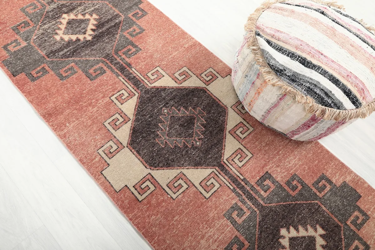 Overhead shot highlighting the central charcoal and beige geometric motifs on the rust runner rug