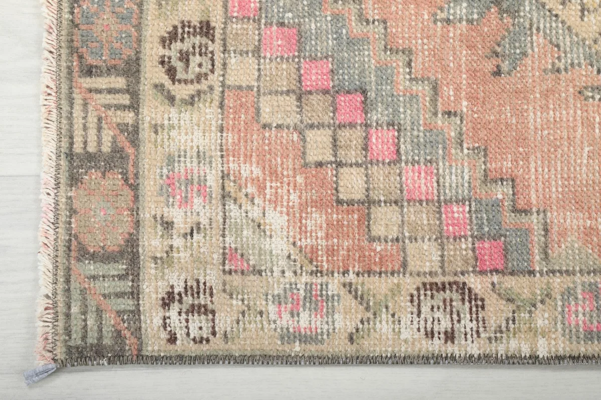 Detailed view of the rug's border design and the varying pile height and wear