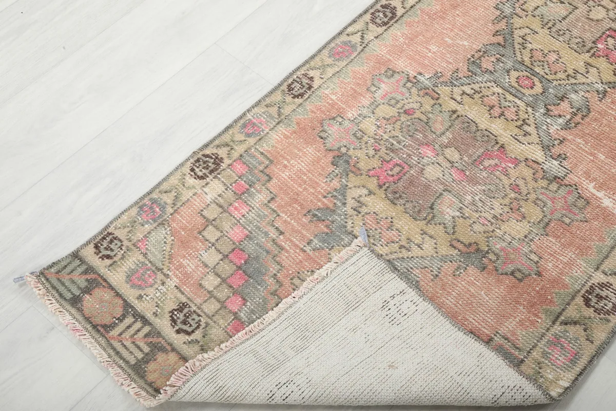 Corner of the rug folded back, revealing the cotton foundation and knotting