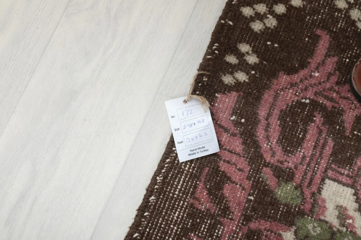 Rug corner with a product tag, indicating its hand-knotted origin and size.