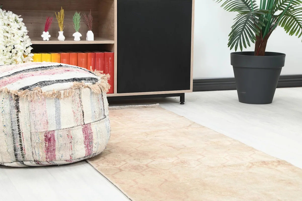 Close-up of the runner rug's pattern near a pouf and a wooden cabinet