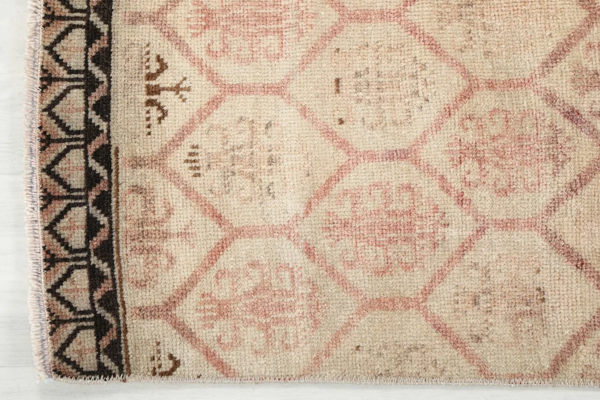 Close-up of the intricate dark brown and black border design at the end of the runner