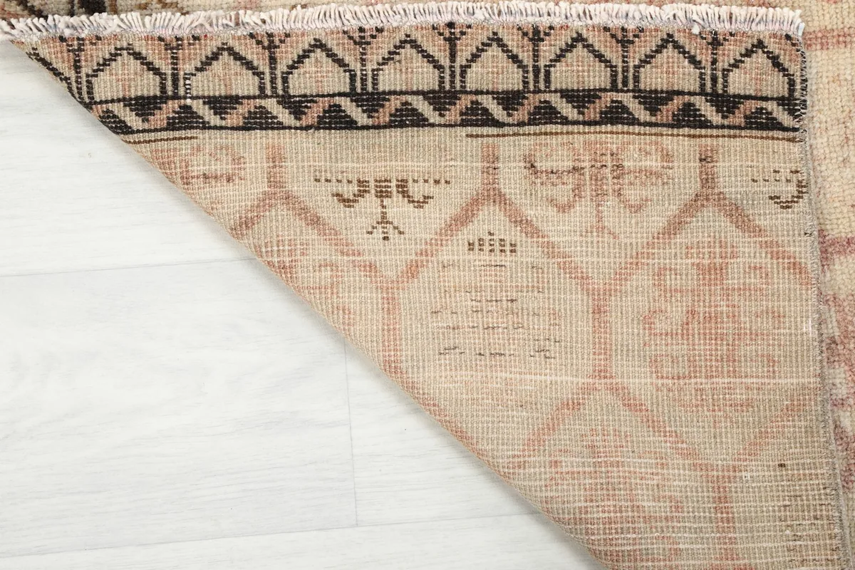 Close-up of the rug's reverse side, revealing the hand-knotted cotton foundation and fringe