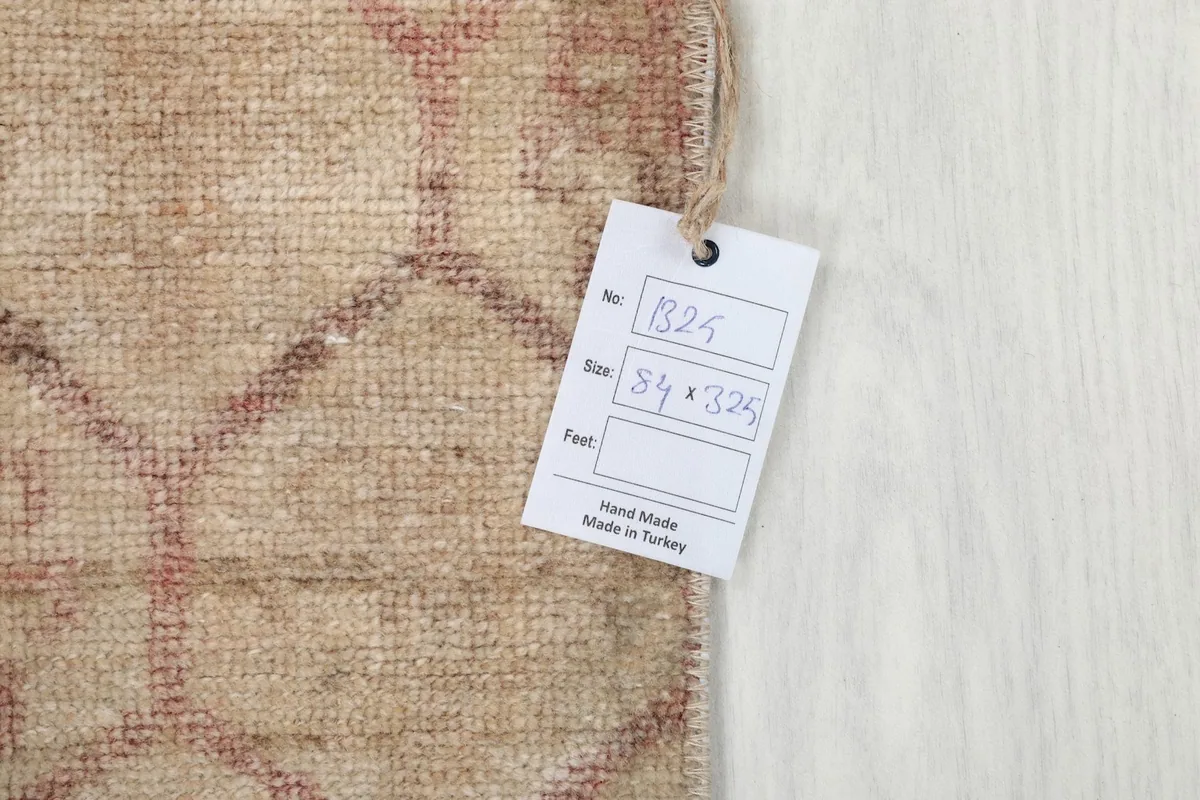 Photo of the rug's tag, indicating its size of 84 x 325 cm and hand-made origin