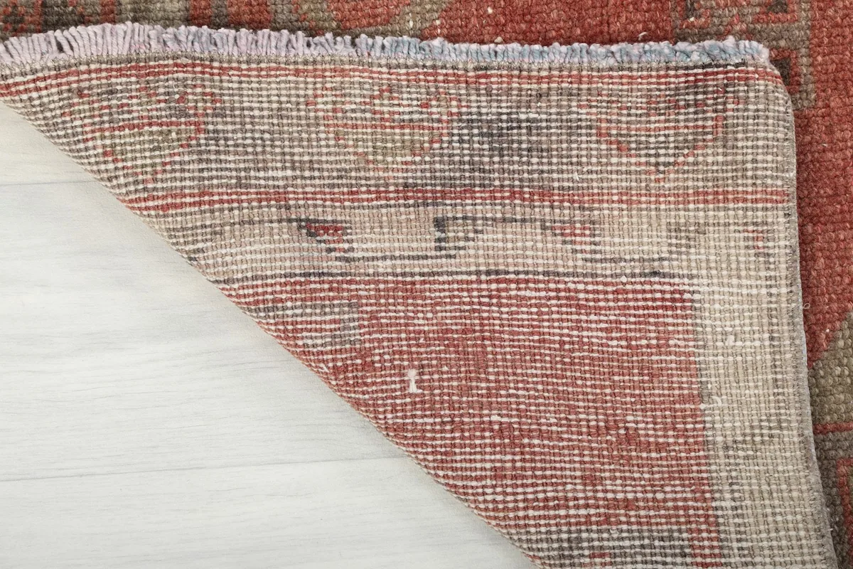 Underside view of the rust runner rug, revealing its hand-knotted cotton foundation.