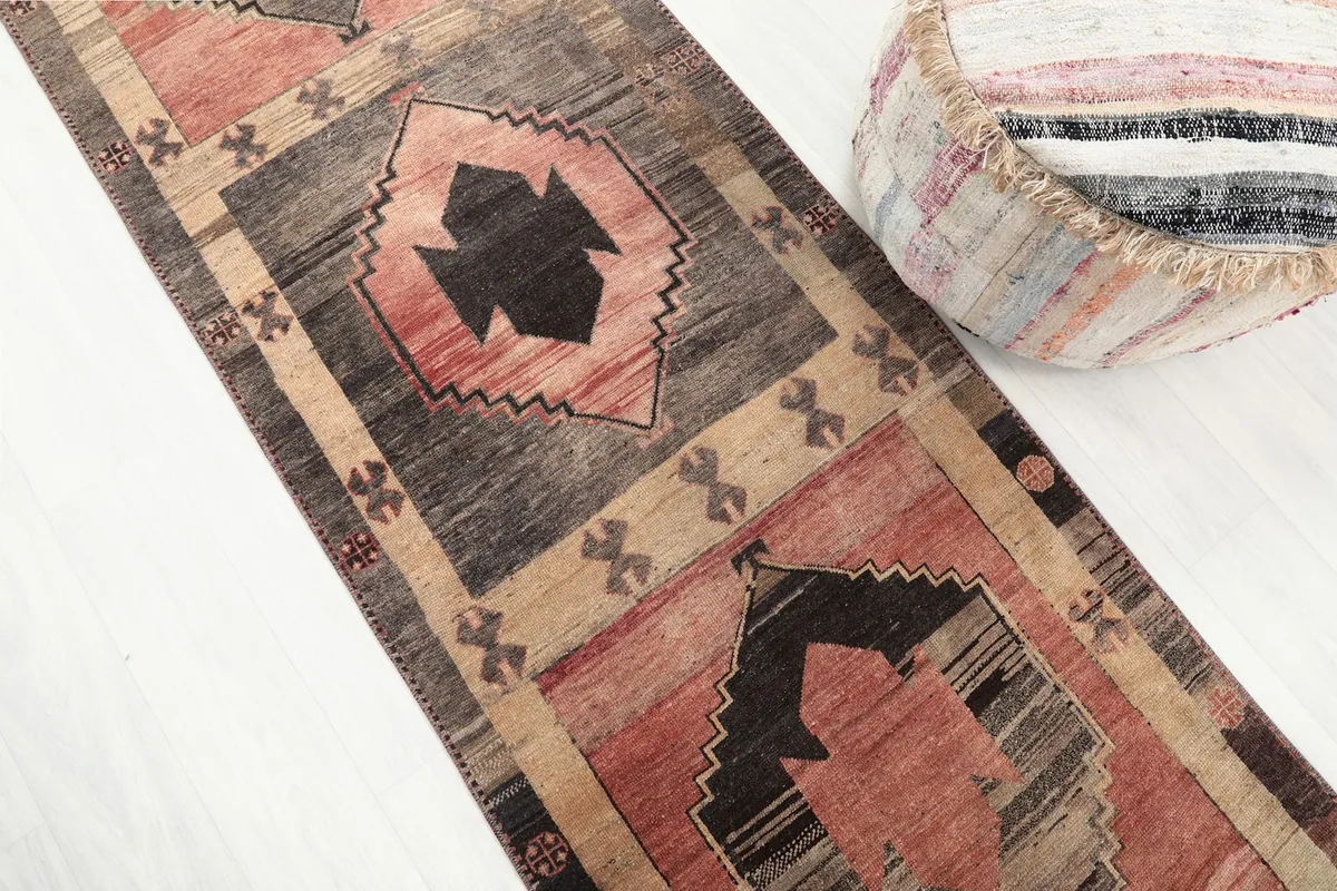 Angled close-up of the runner rug's geometric design and texture, with a decorative pouf nearby
