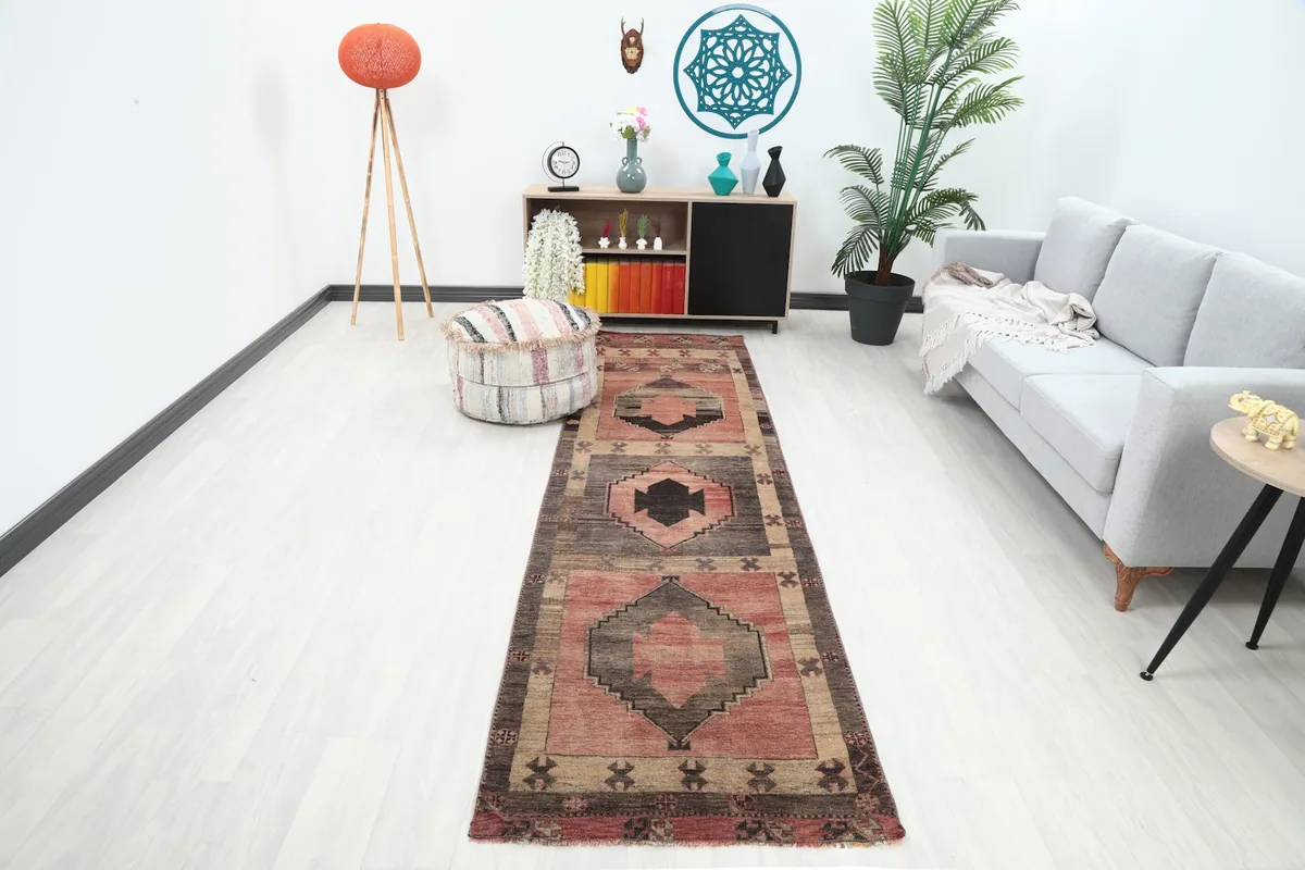 Vintage Anatolian runner rug in a room setting, showing its length and colors next to a sofa
