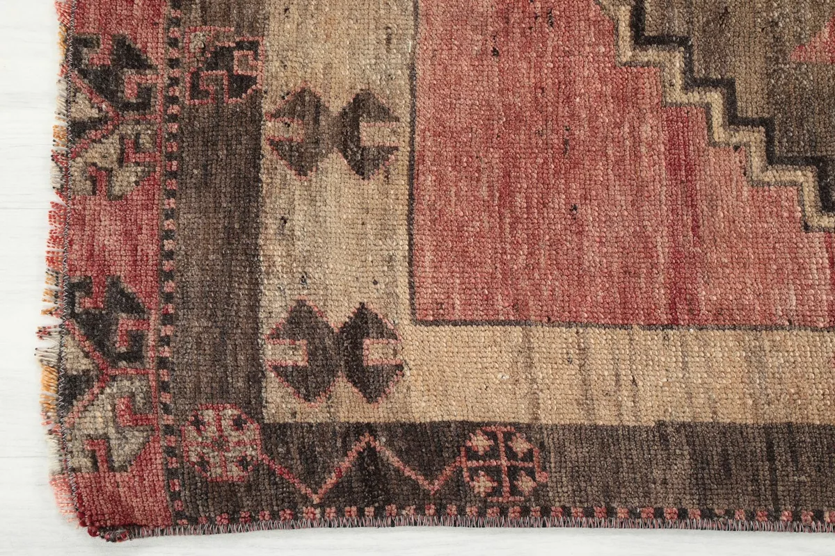 Close-up of the rug's border design and corner, showing the distinct pattern and colors