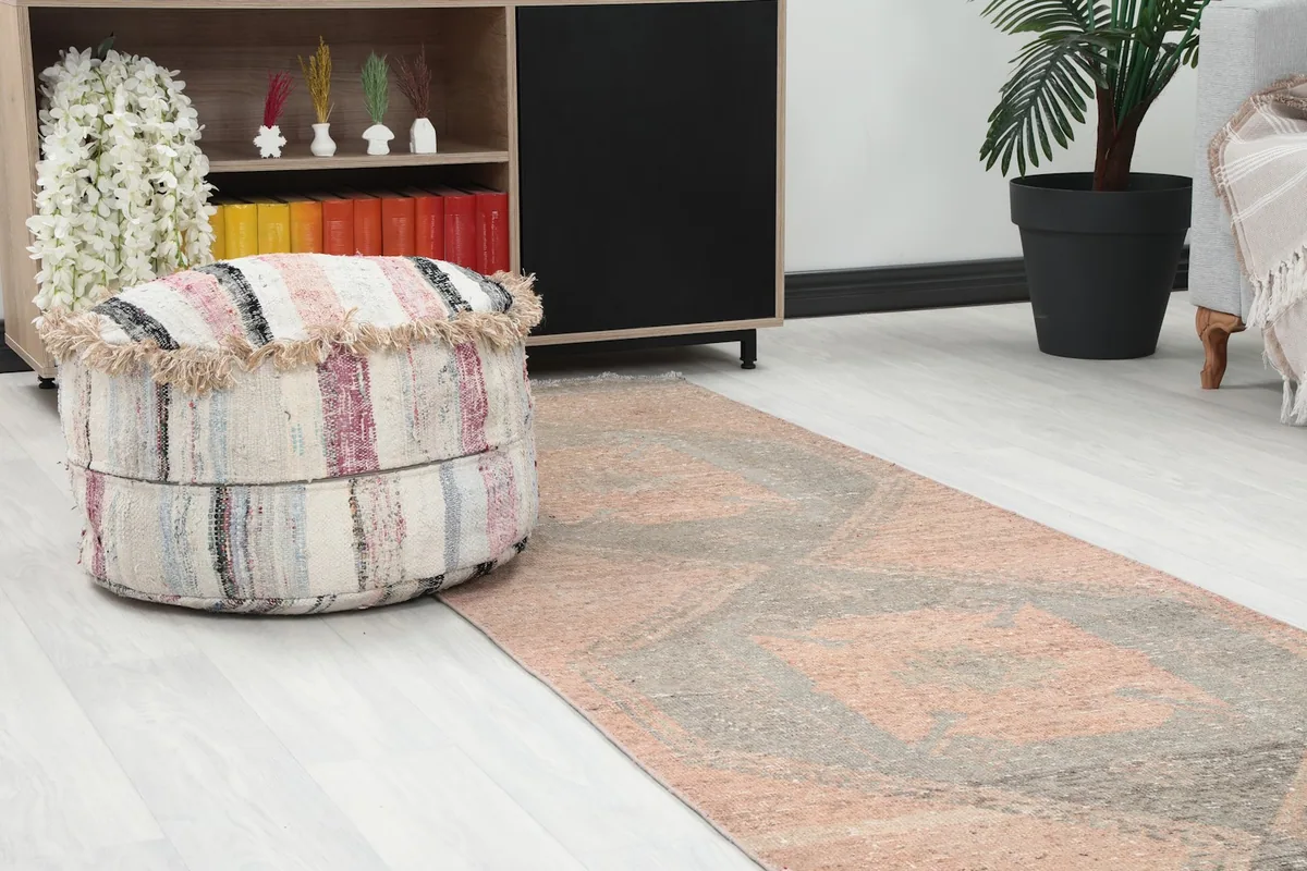 Close-up view of the runner rug's pattern next to a striped ottoman and a bookshelf.
