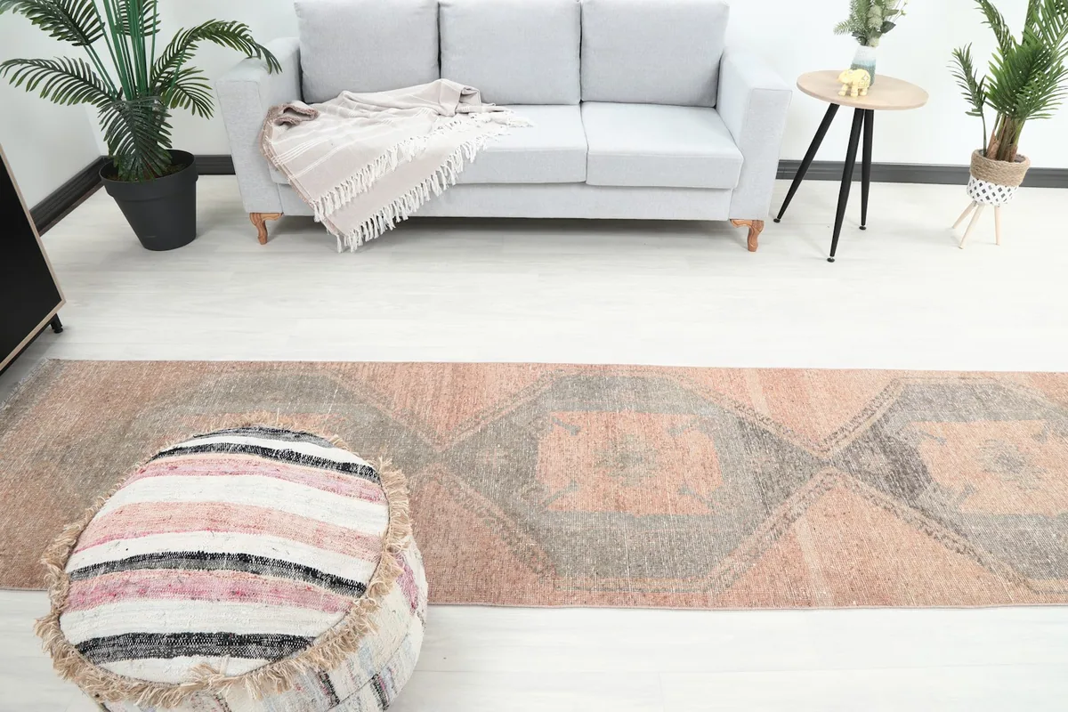 Overhead view showing the length of the runner rug in a room, with a sofa and ottoman visible.